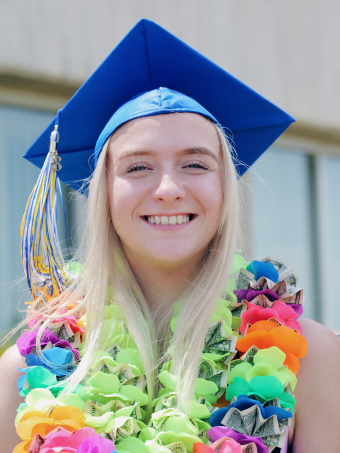 A person in a graduation cap with a lei on